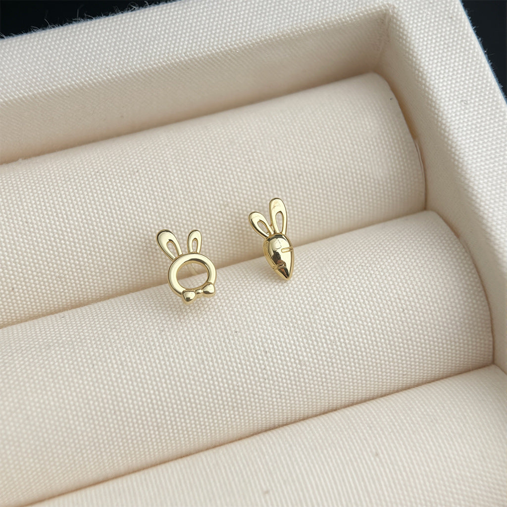 Gold bunny-shaped earrings on a textured beige