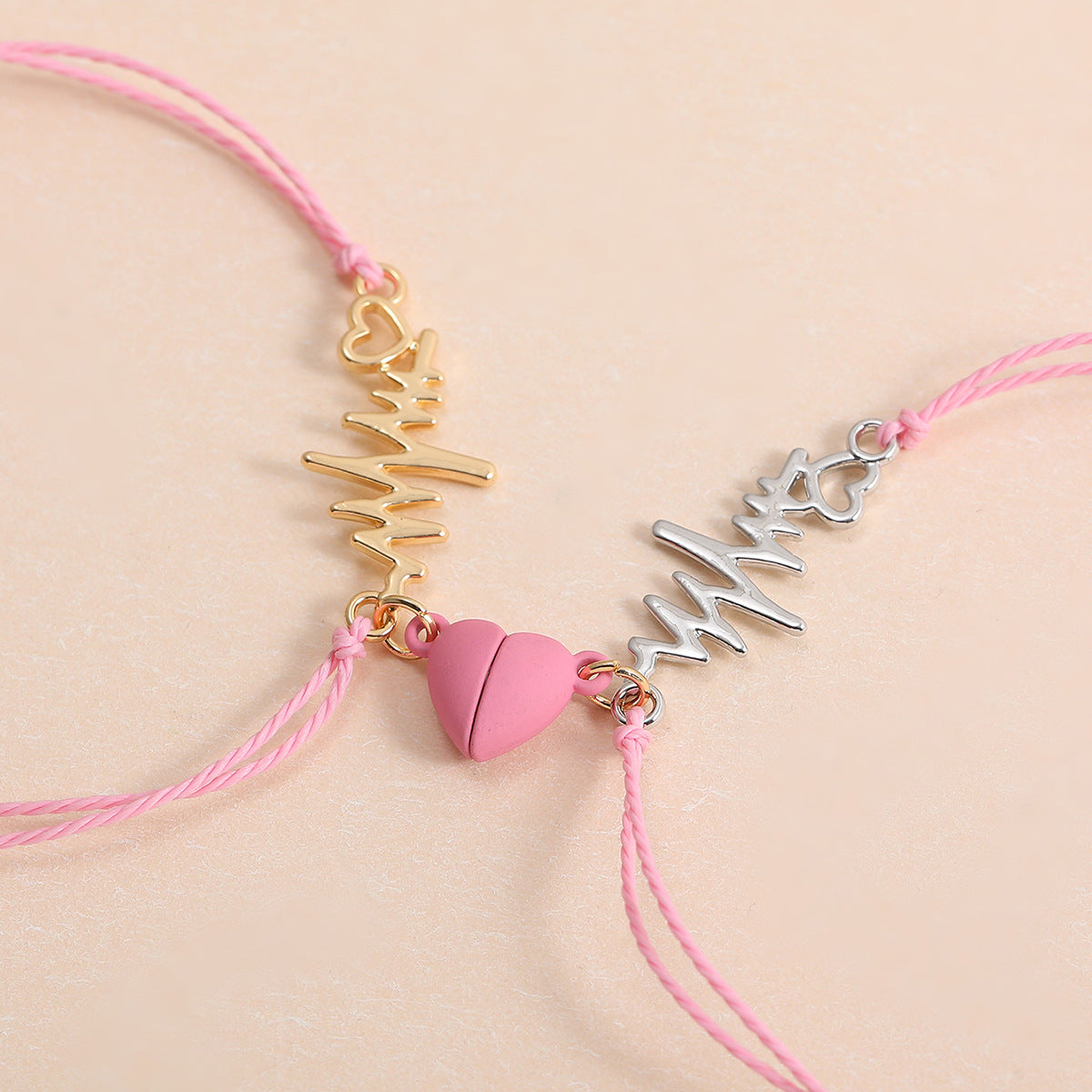 Two pink bracelets with gold and silver charms on a beige background