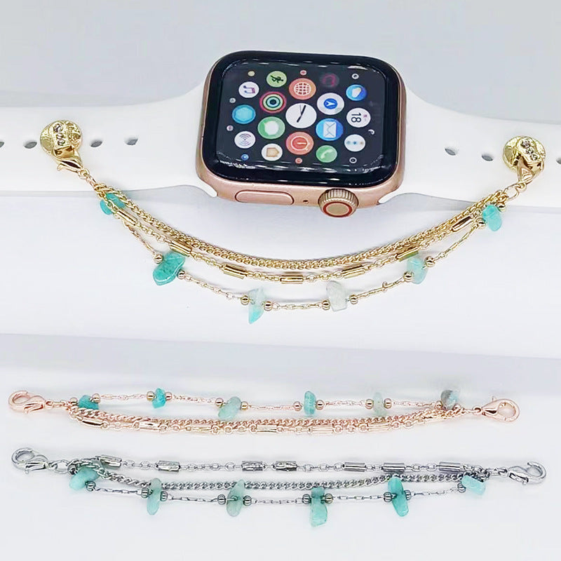 Smartwatch with a gold bracelet featuring turquoise stones on a white surface